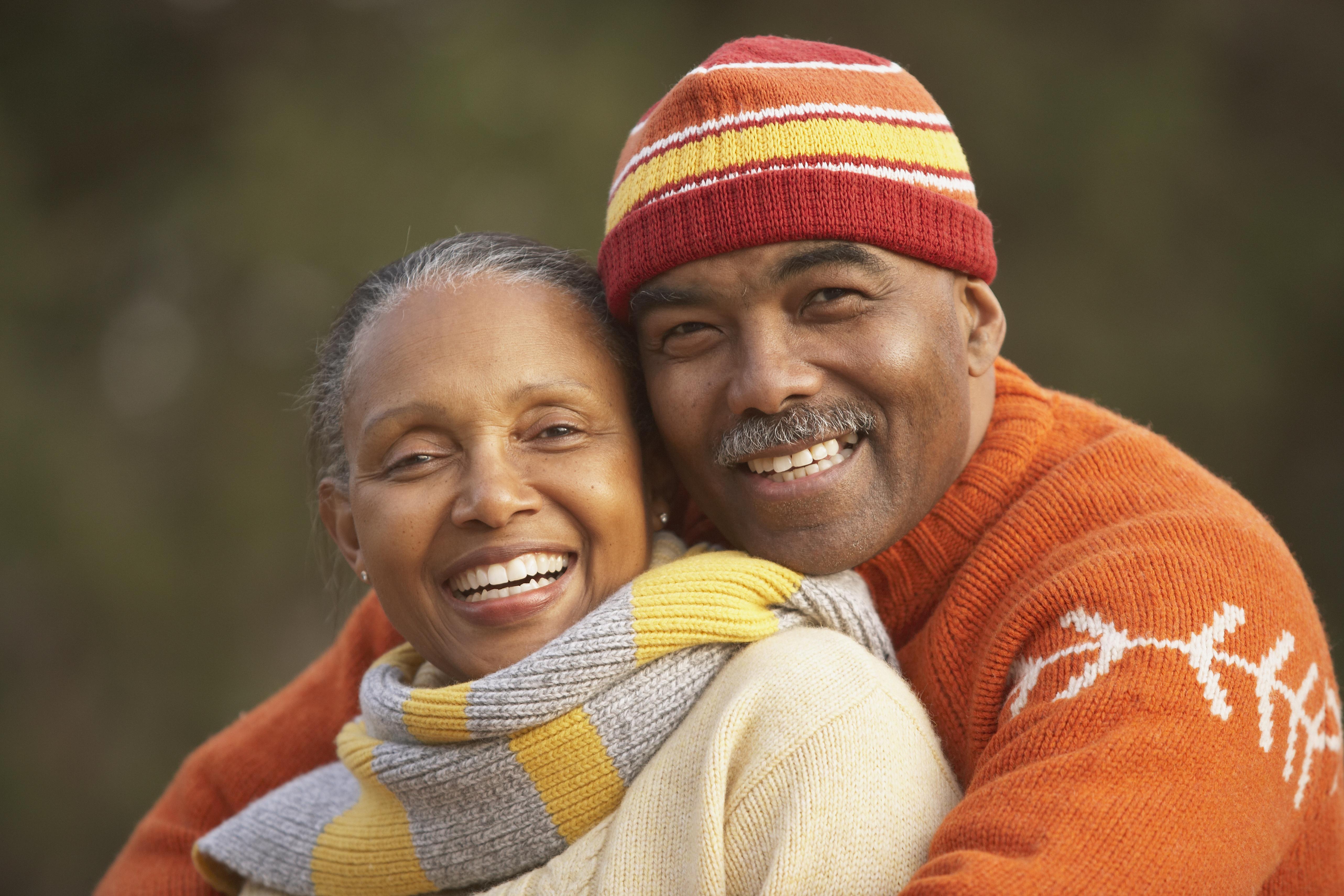 Middle-aged African American couple hugging outdoors