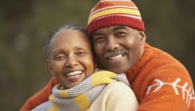 Middle-aged African American couple hugging outdoors