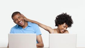 Woman joking with man as they work on laptops