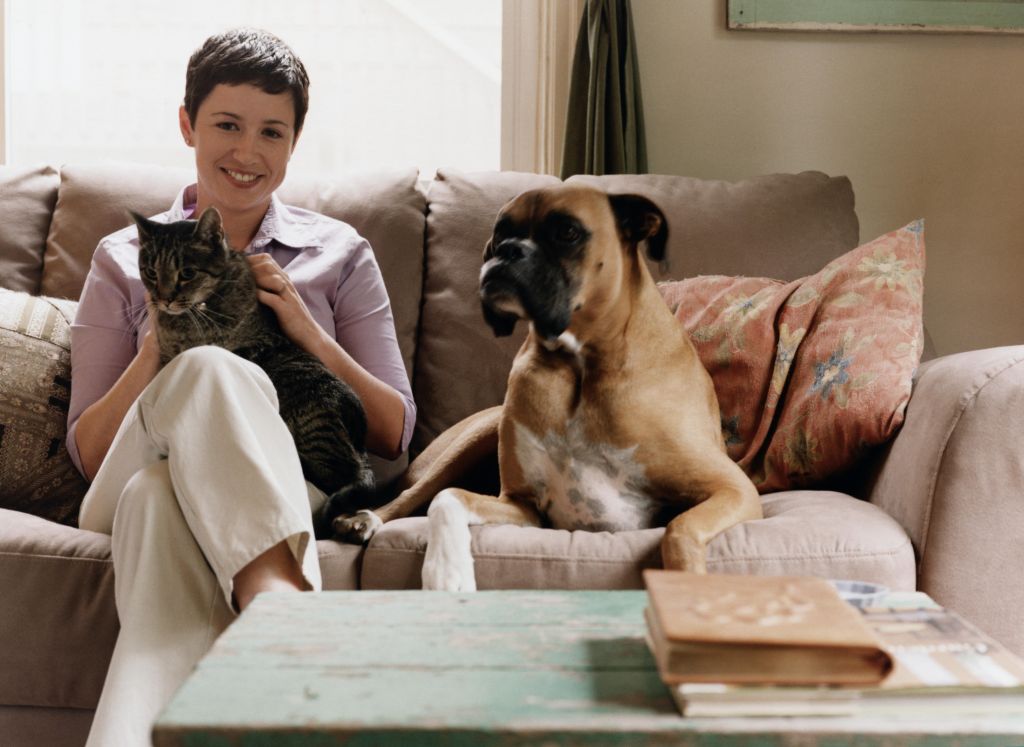 Young Woman Sitting on Couch with Dog and Cat