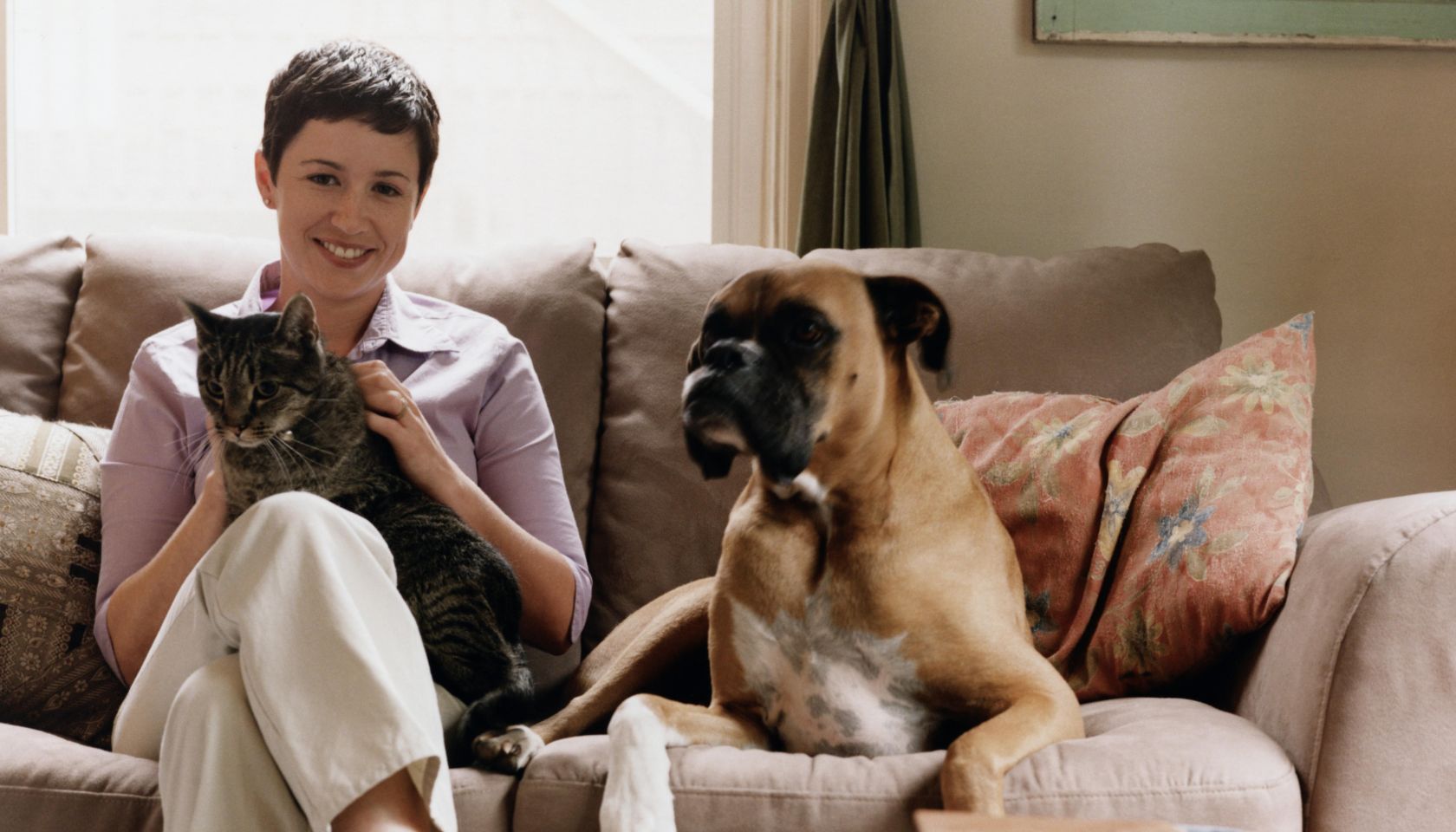 Young Woman Sitting on Couch with Dog and Cat