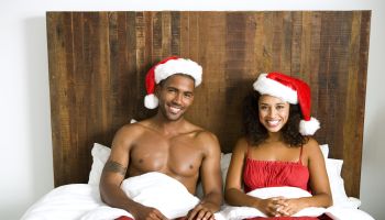 Portrait of young couple wearing santa hats in bed