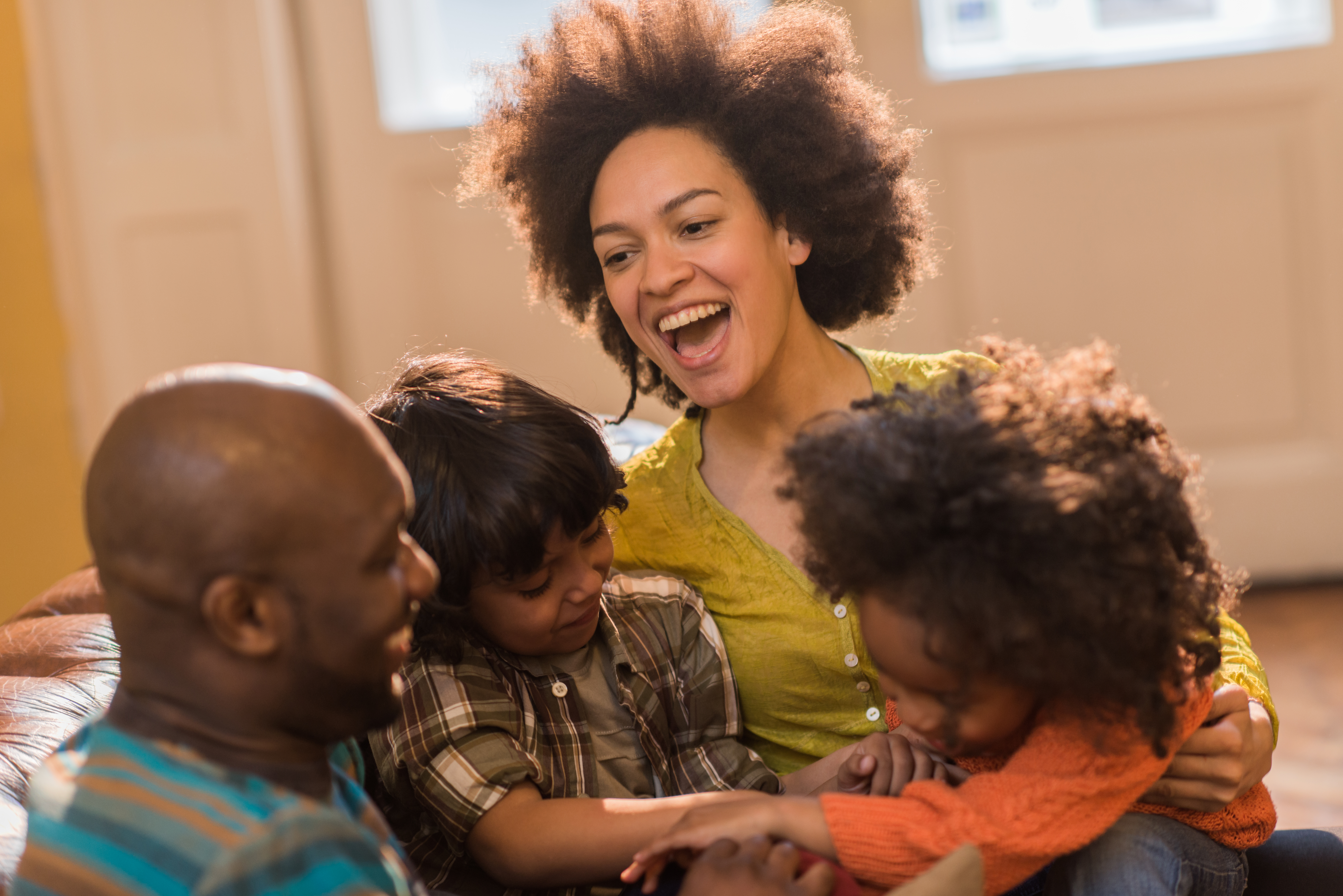 Cheerful African American parents and their small children at home.