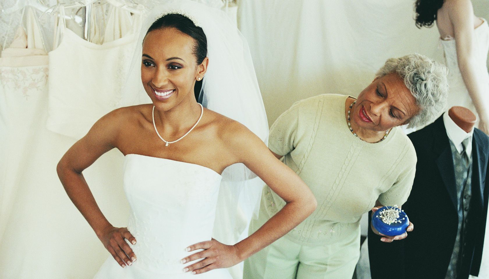 Shop Assistant Helping a Woman Try on a Wedding Dress in a Clothes Shop