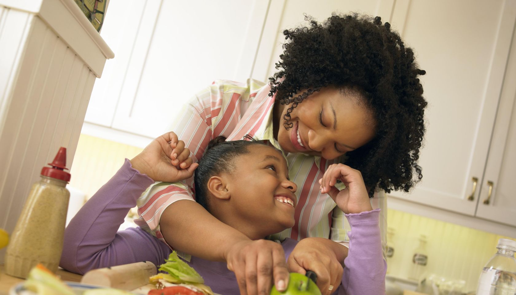 Mother Stands With Her Young Daughter in the Kitchen, Chopping an Apple for Her Lunch