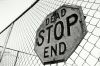 'Stop, Dead End' sign on chain link fence (B&W)