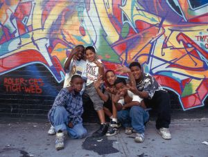 Small group of teenagers in front of graffiti on wall
