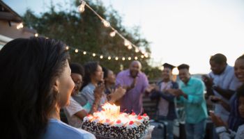 African American mother serving graduation cake to family on summer deck