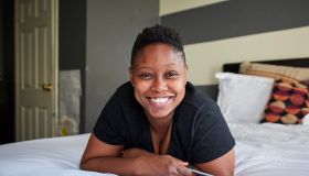 Smiling Black woman laying on bed holding cell phone