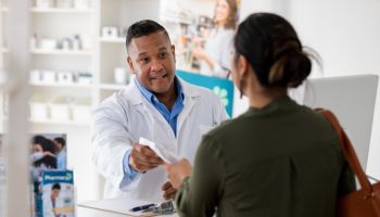 Pharmacist hands prescription to customer