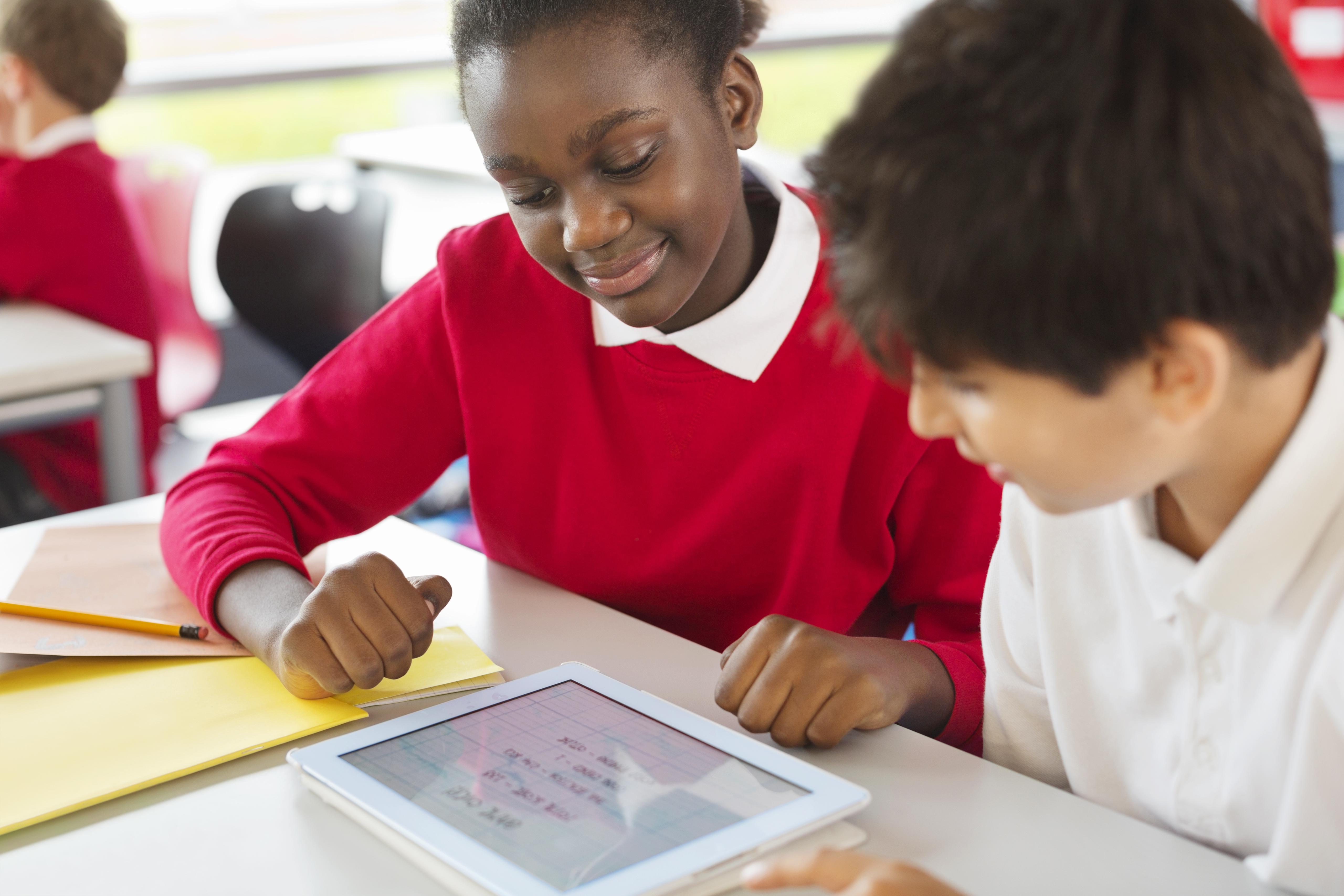 Students sharing digital tablet in classroom
