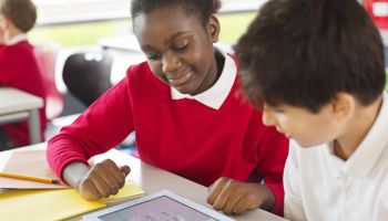Students sharing digital tablet in classroom