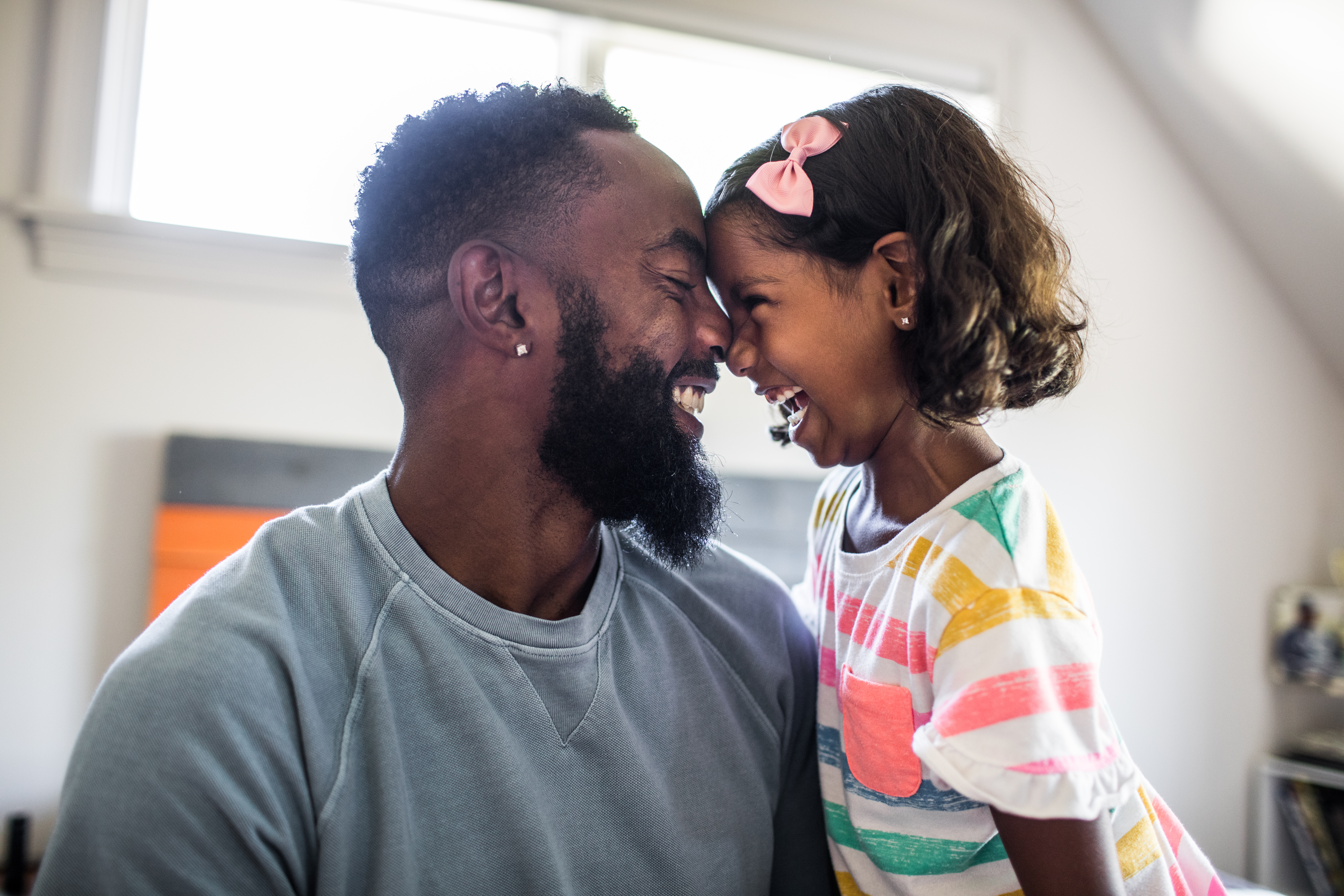 Father and daughter laughing in bedroom - stock photo
