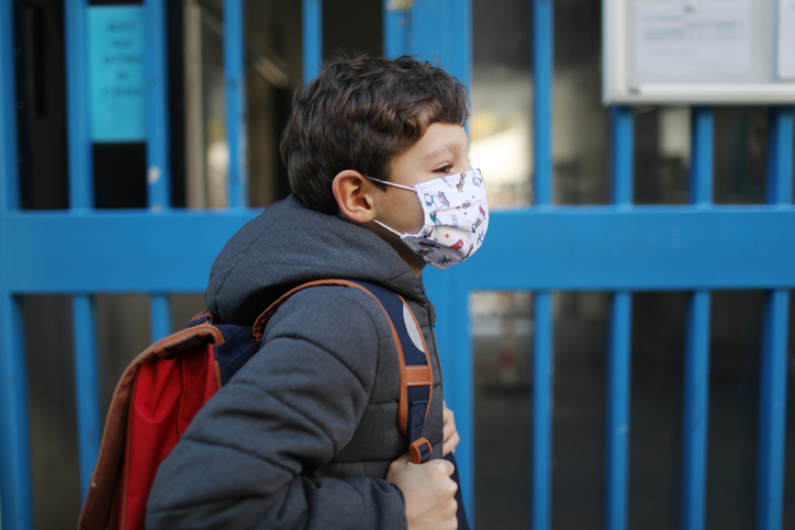 Portrait of a boy wearing a protective face mask in front of school