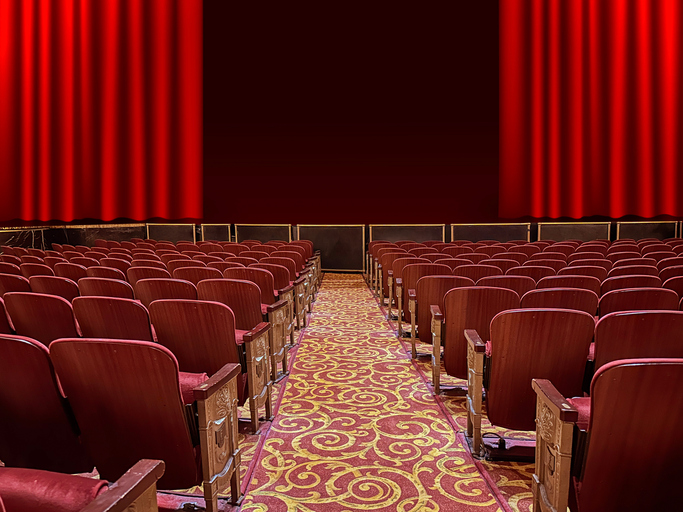 Empty Theater Auditorium with Red Stage Curtains and Seats